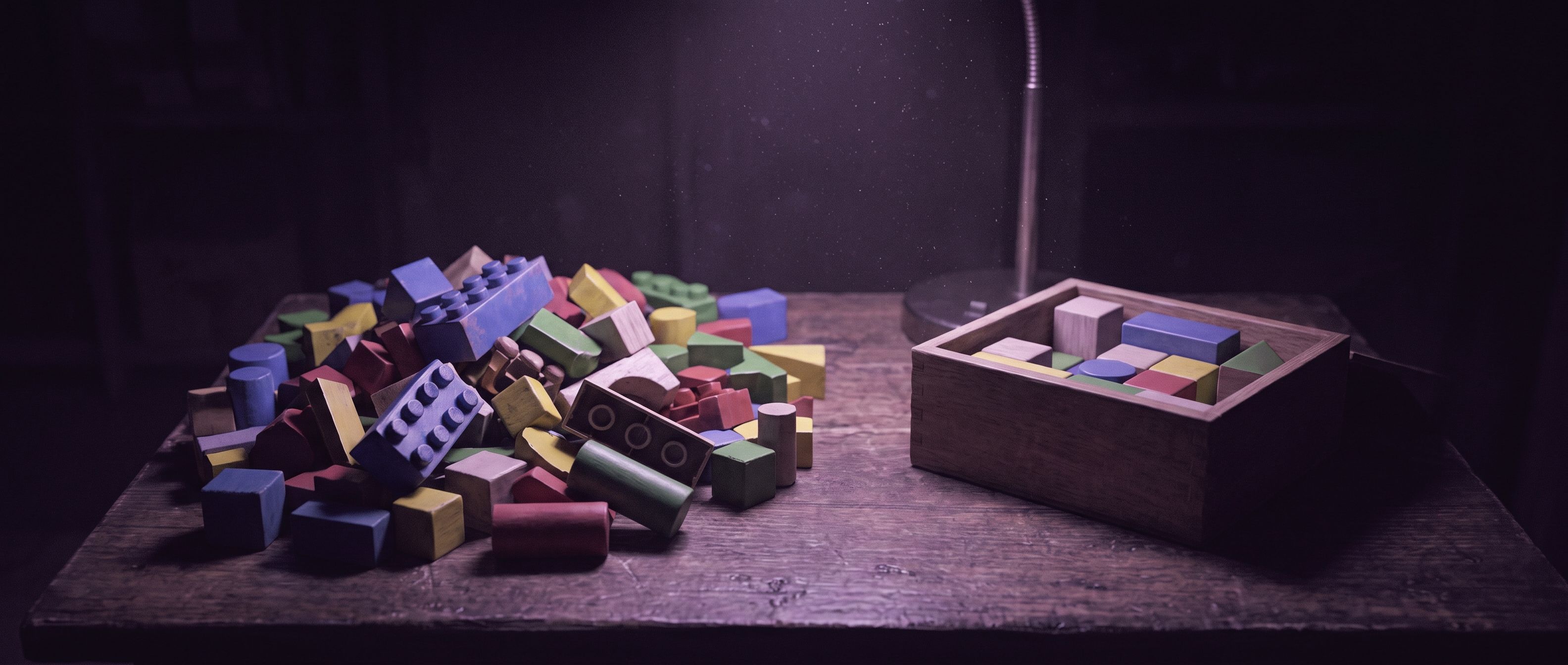 Un montón desordenado de bloques de juguete de colores junto a una caja de madera con unos pocos bloques ordenados.